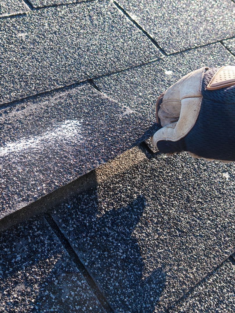 A man is standing on top of a roof looking at a clipboard.