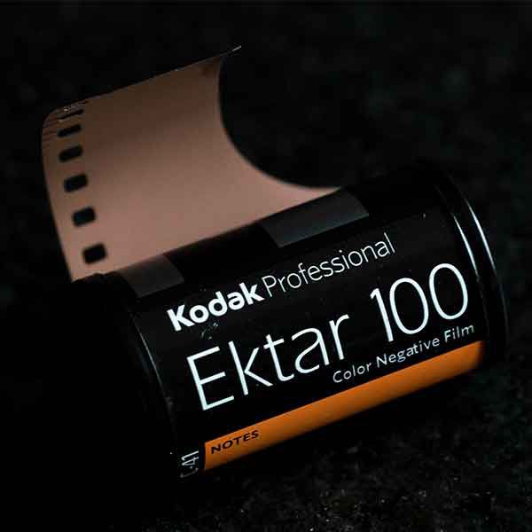 Kodak Professional Ektar 100 color negative film canister with a film strip on black background