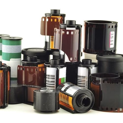 Assorted rolls of photographic film canisters in black, brown, and silver on a white background