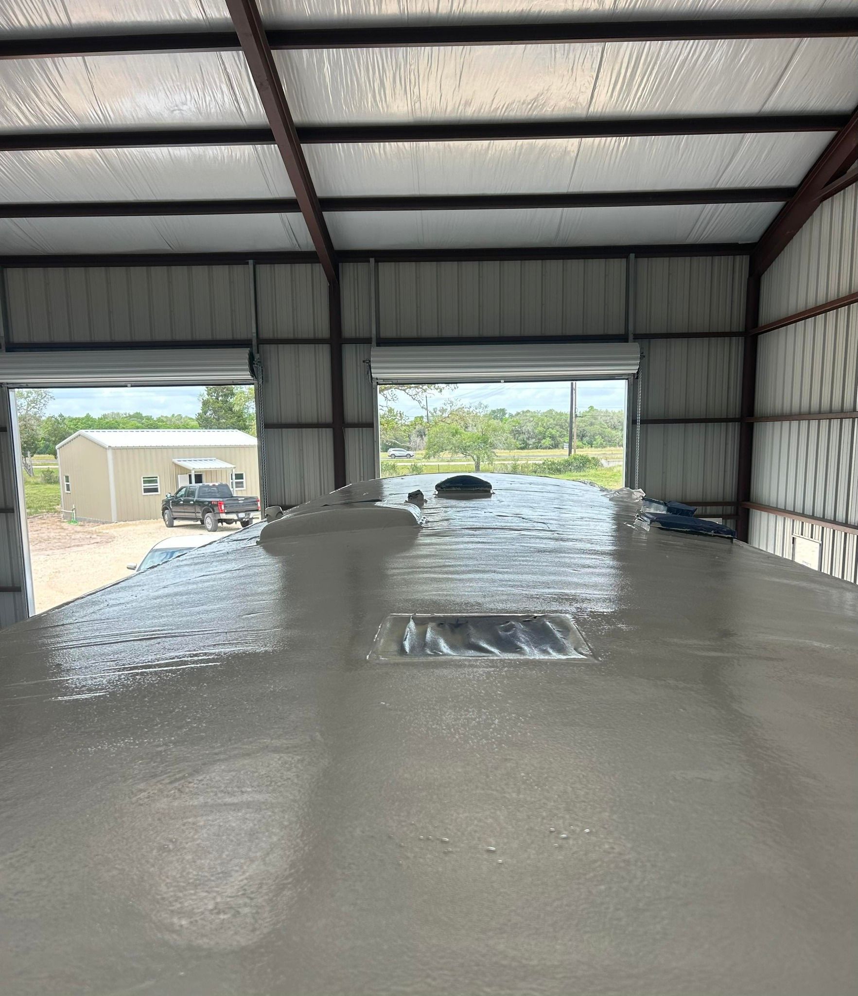 The inside of a building with a concrete floor and a garage door open.