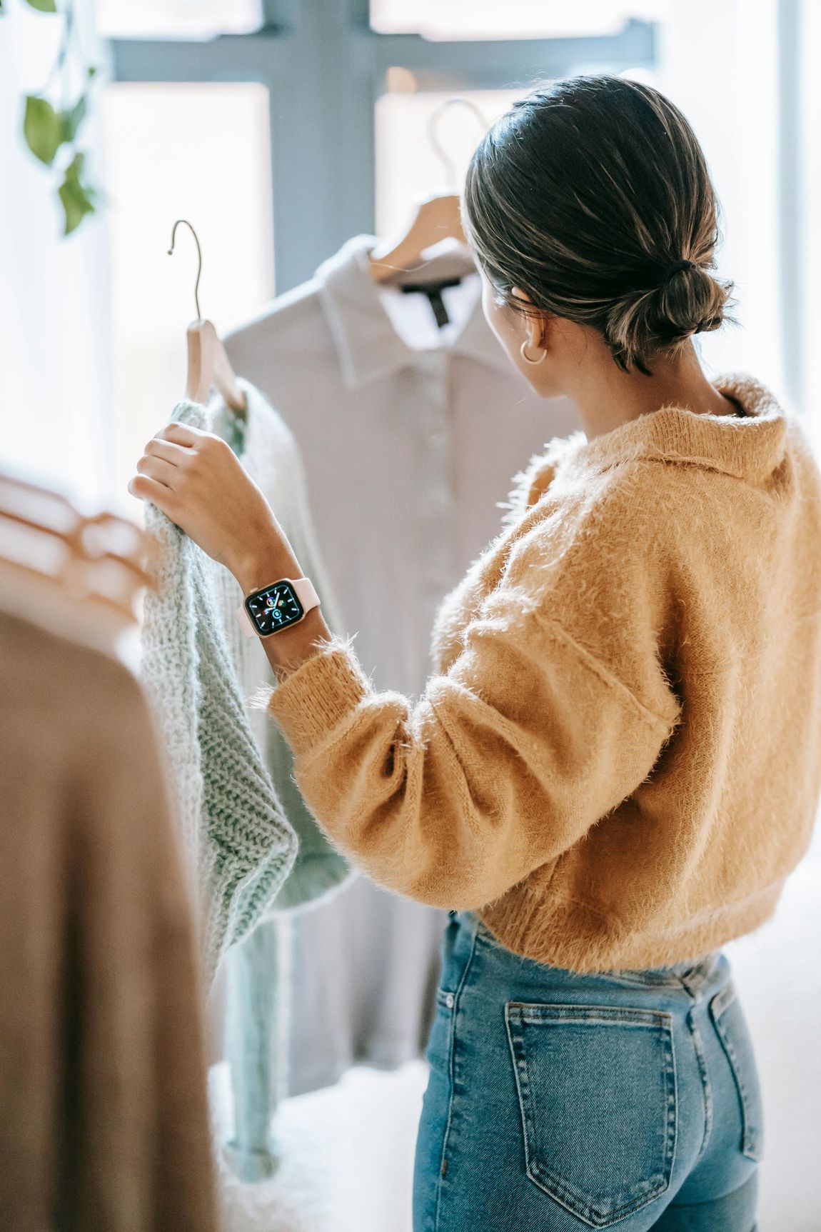 A woman is looking at clothes on a rack in a store.