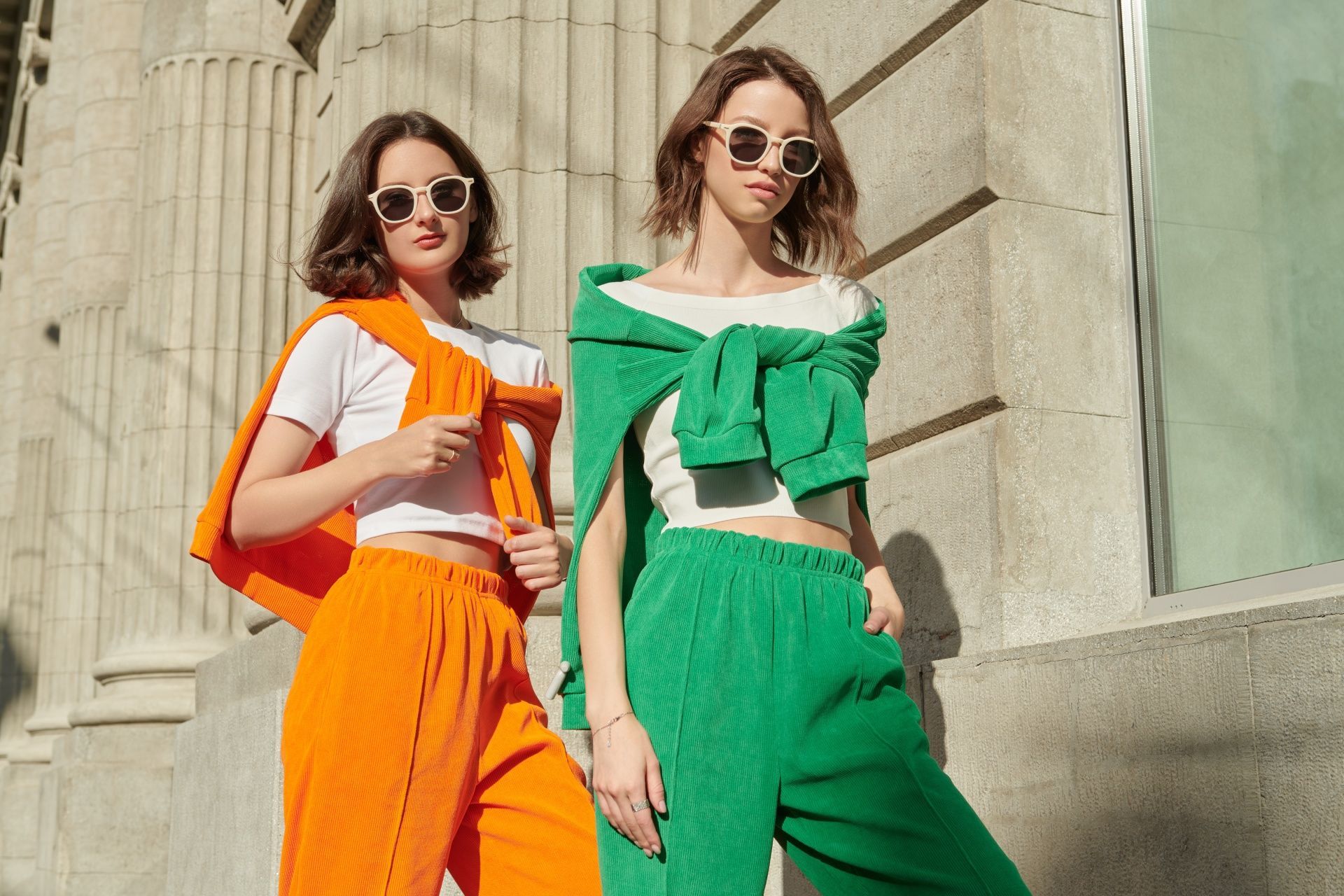 Two women are standing next to each other wearing orange and green clothes.