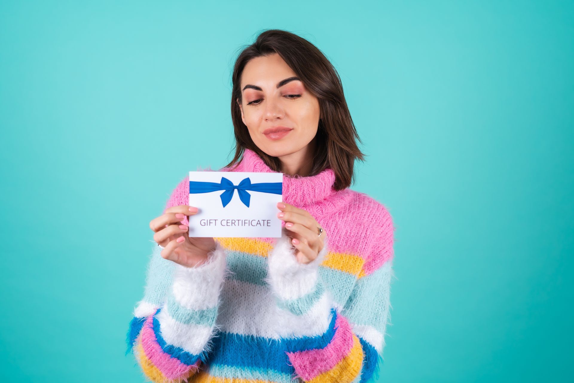 A woman in a striped sweater is holding a gift card with a blue bow.