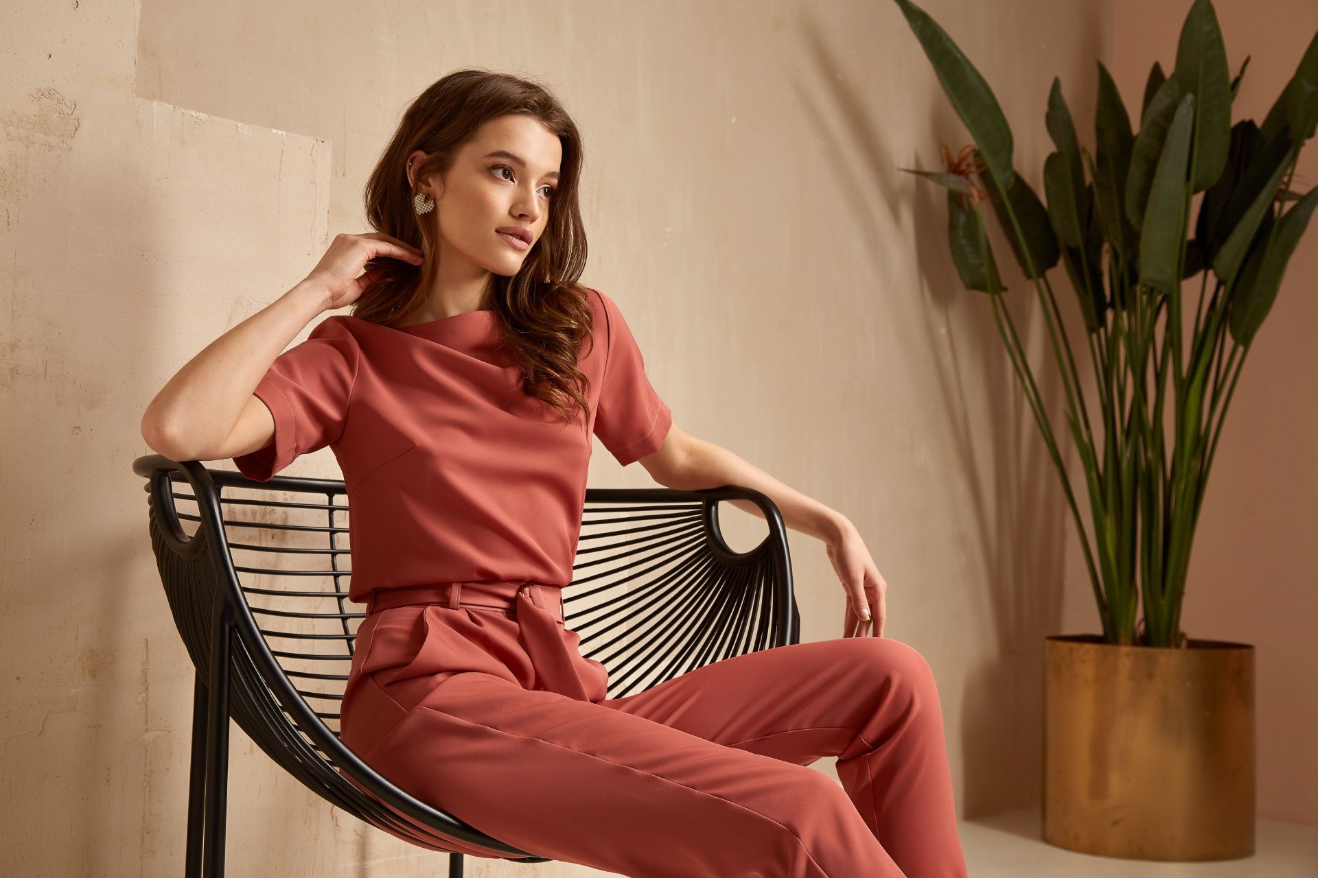 A woman is sitting in a chair next to a potted plant.