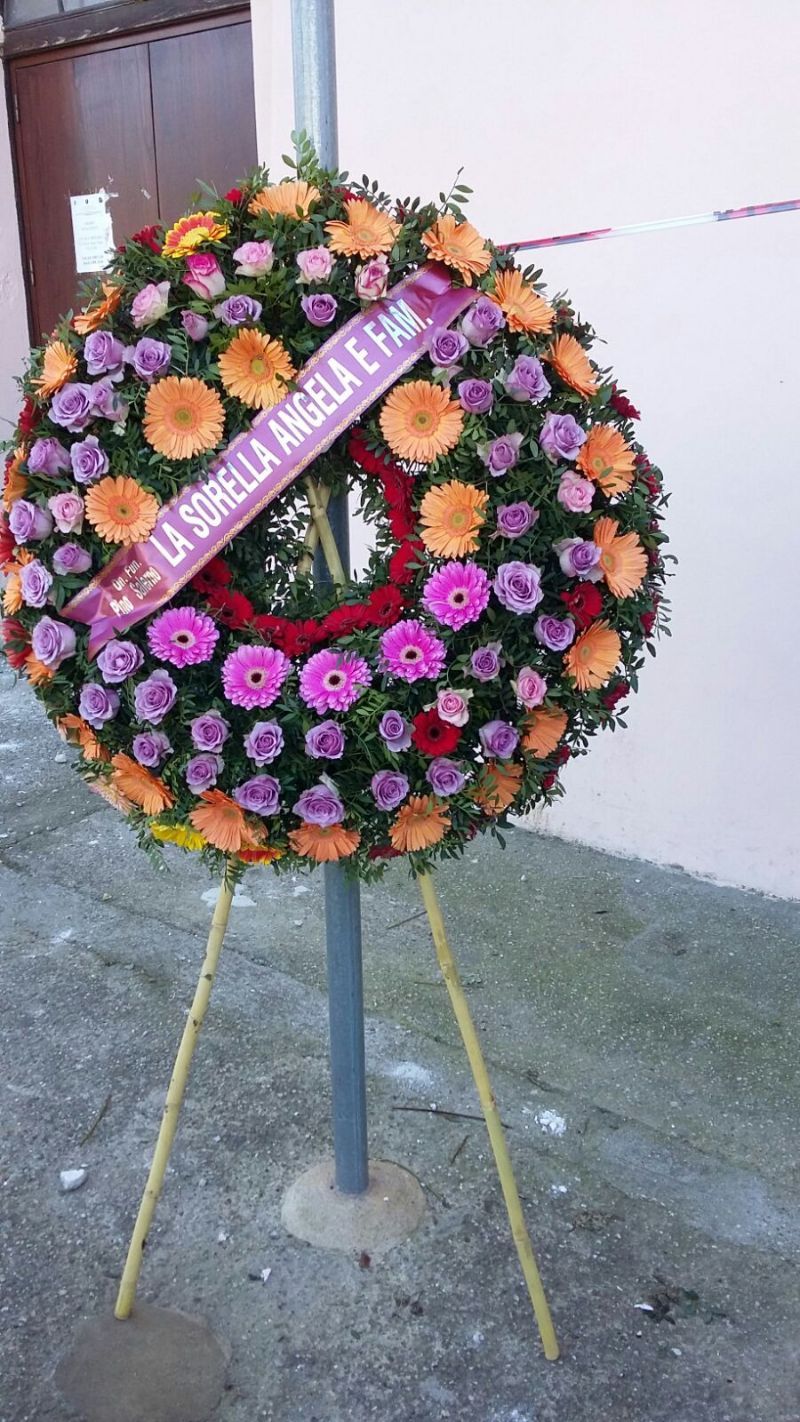 Corona di fiori su un supporto, con un nastro con la scritta