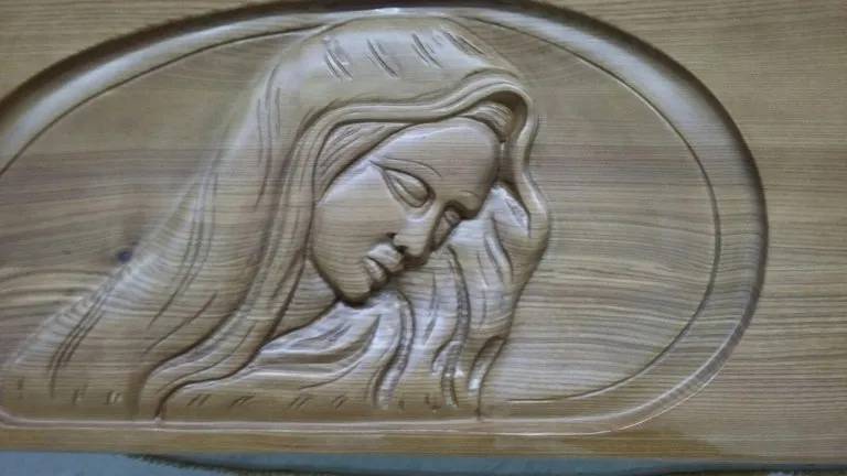 Rilievo in legno intagliato raffigurante una donna con capelli fluenti e testa china, racchiusa in una cornice ovale.
