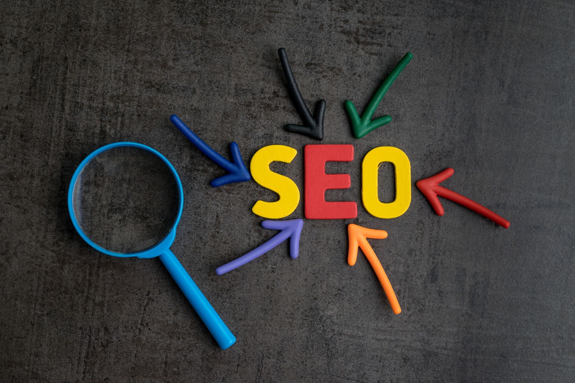 The word SEO is surrounded by colorful arrows and a magnifying glass. Mahogany Tech 