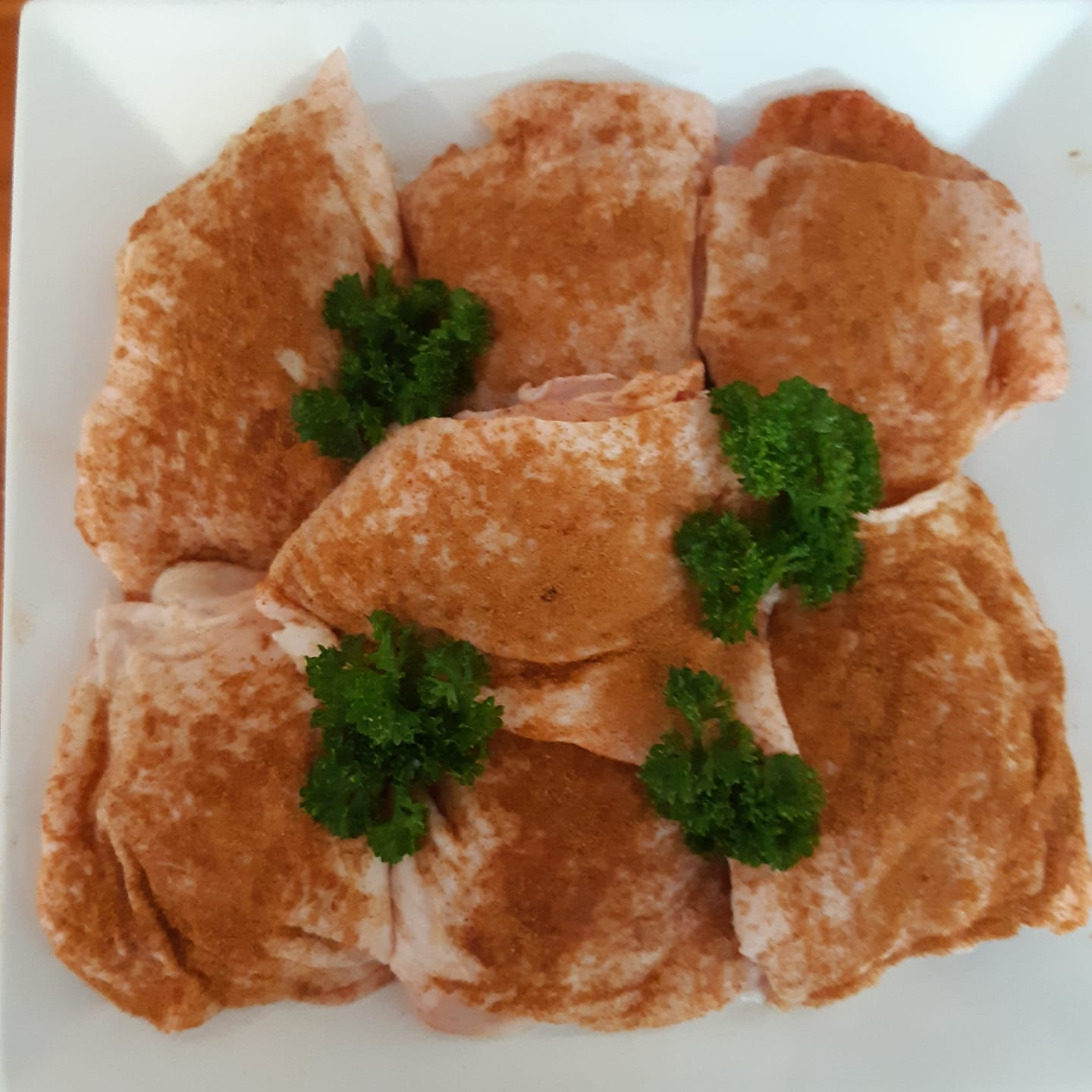 Raw, Seasoned Chicken Thighs on a White Plate — Drovers Meats in Coffs Harbour, NSW