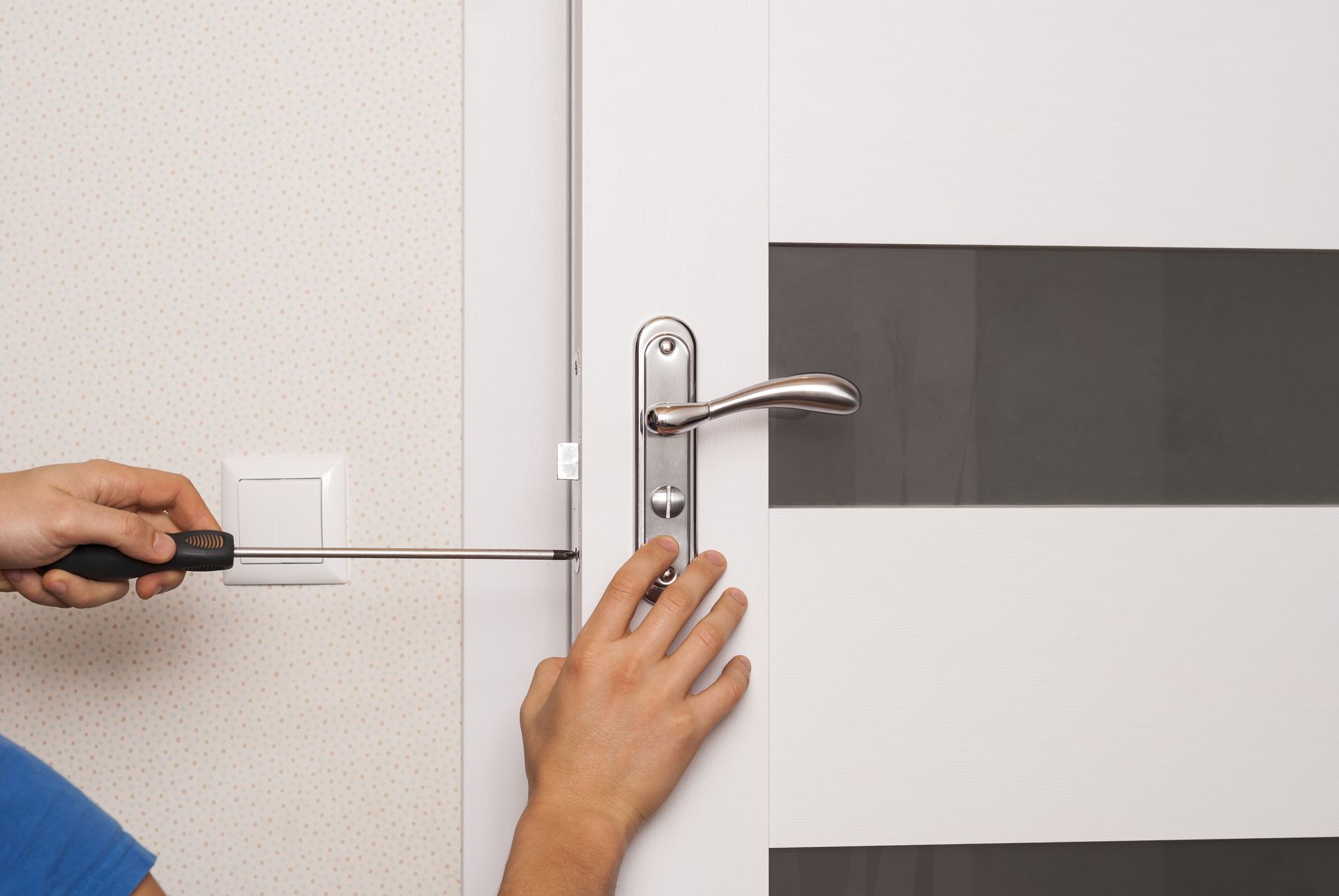 Person using a screwdriver to install a door handle on a white door