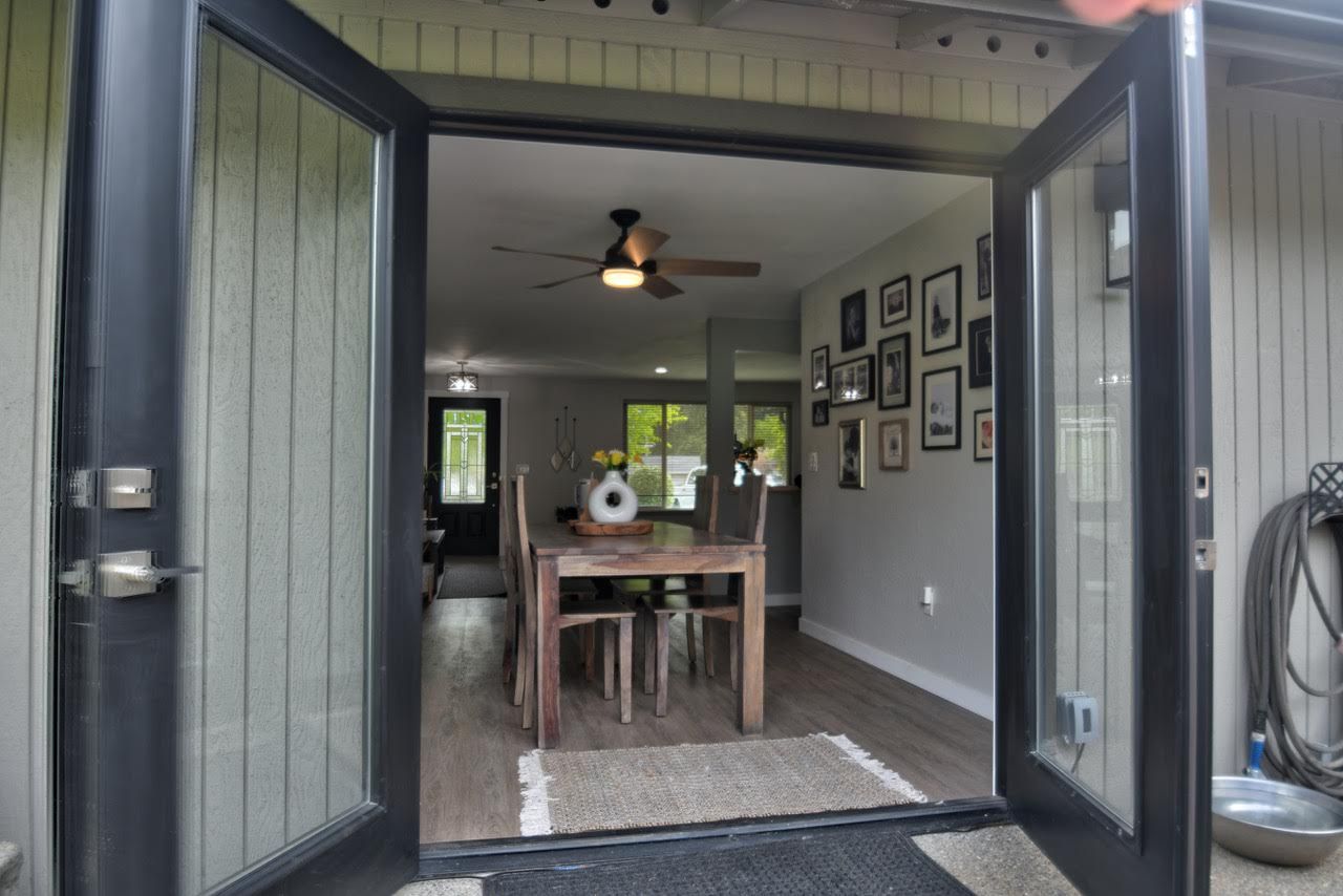 Open double doors lead into a dining room with a table, chairs, and artwork on the wall.