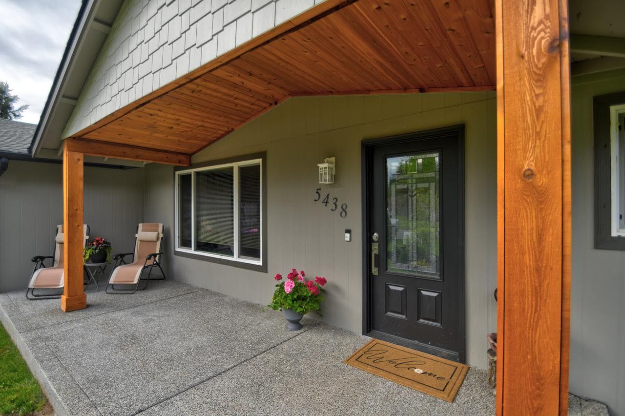 Covered porch with chairs, door, and potted flowers; house number 3438.