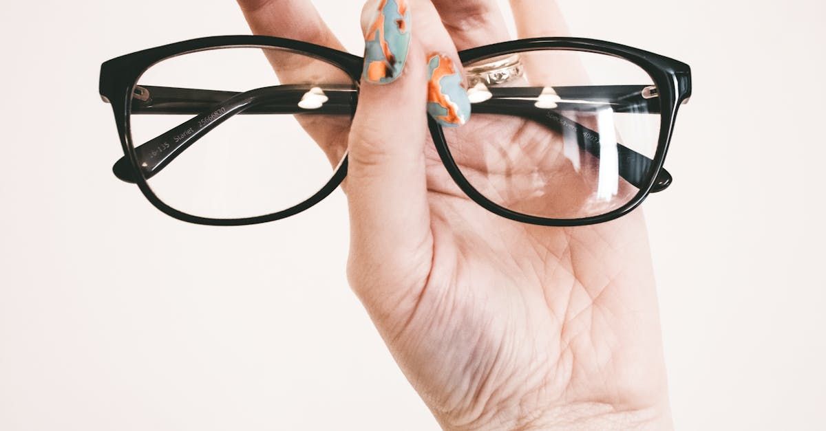 A woman 's hand is holding a pair of glasses.