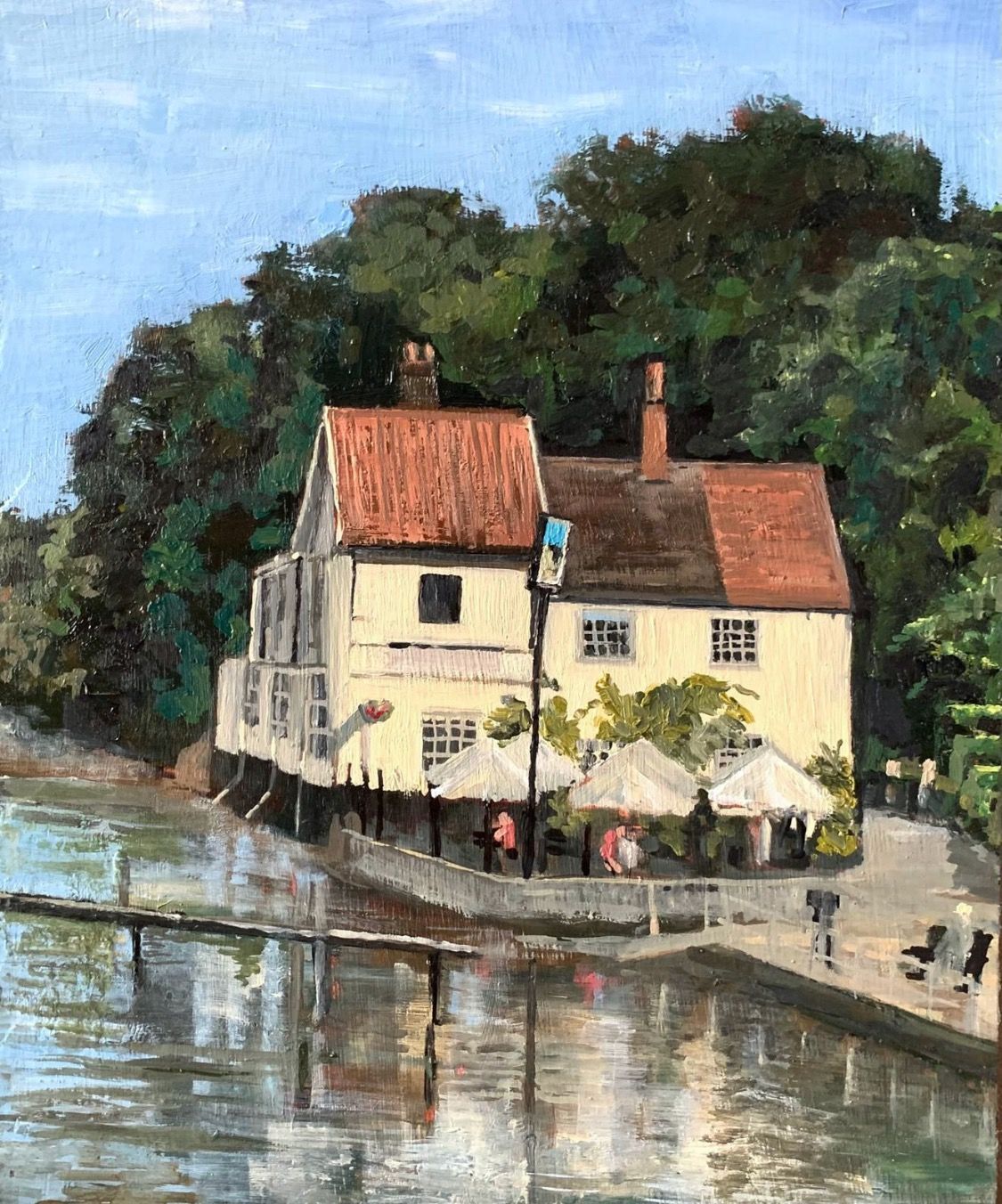 Waterfront house with red roofs and trees reflected in calm water