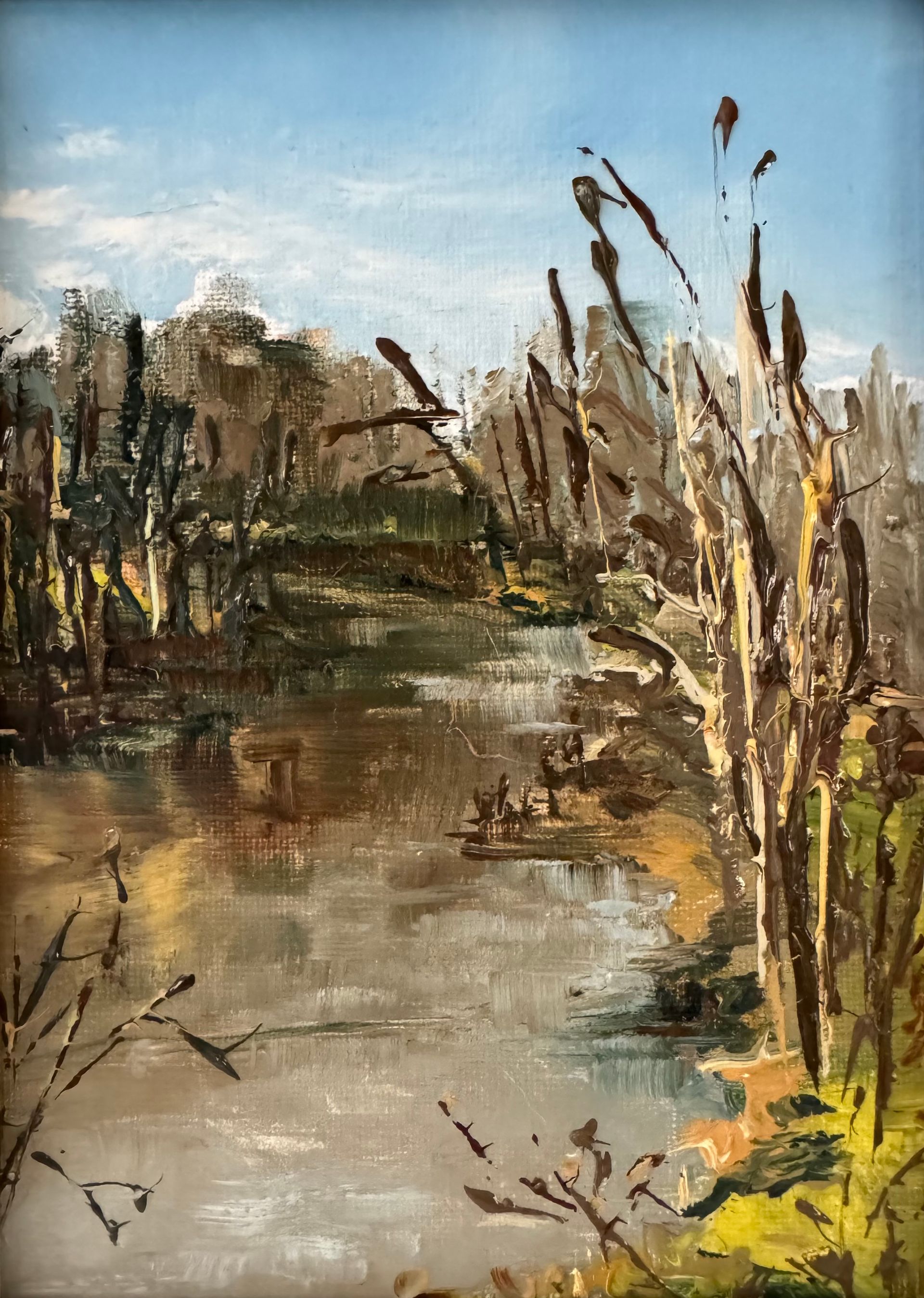 Marsh landscape with reeds, calm water, and distant trees under a blue sky
