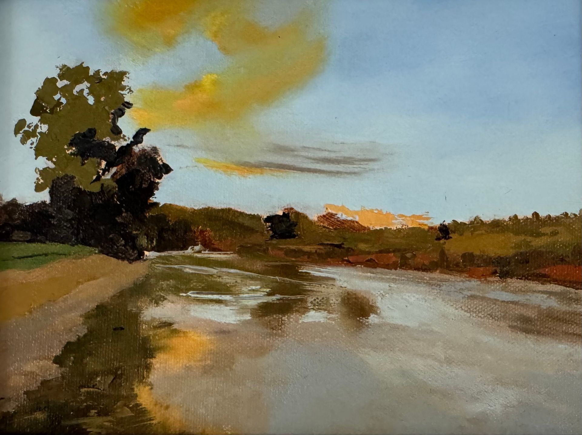 Painterly landscape of a riverbank at sunset, with a tree on the left and reflections on calm water