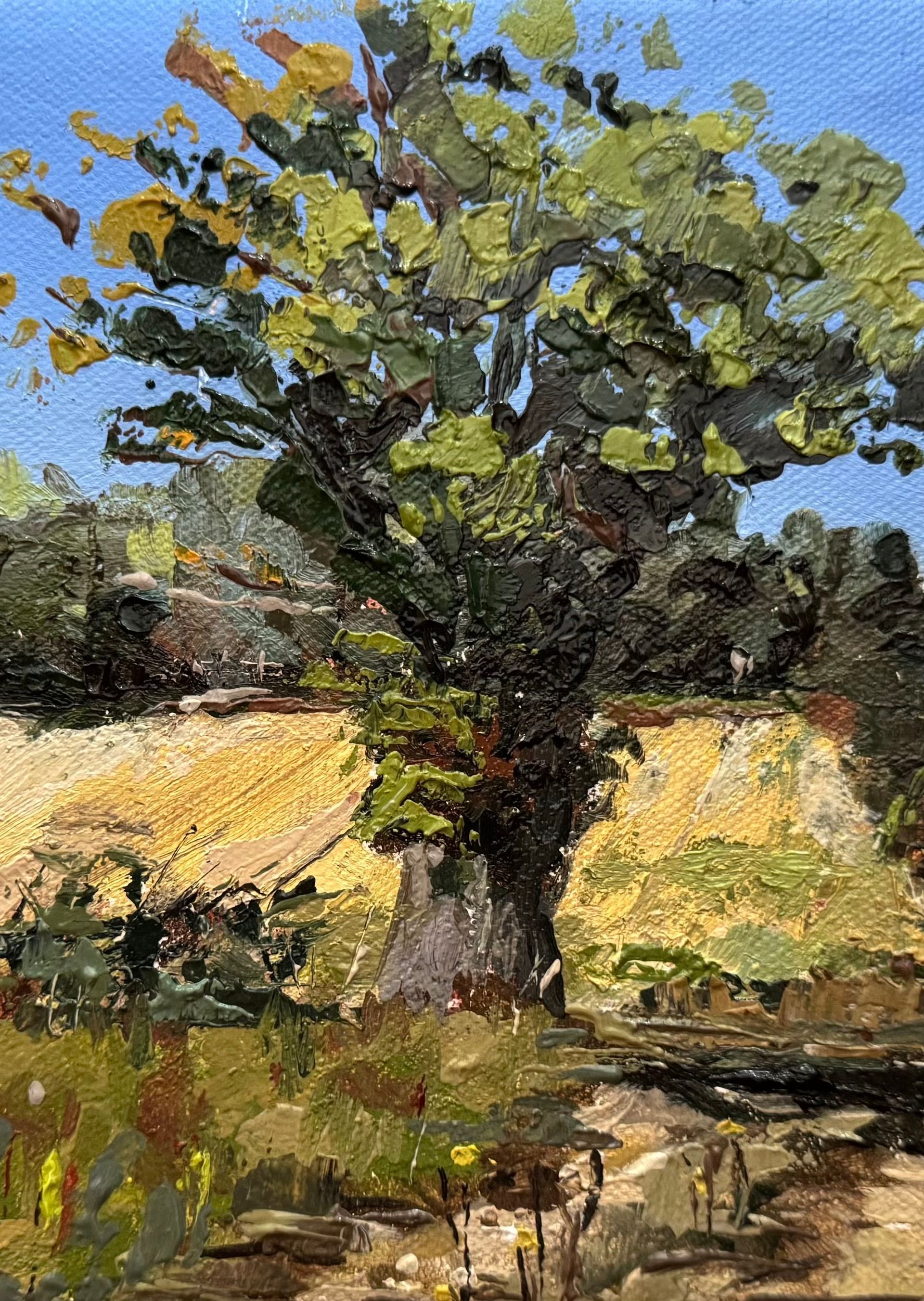 A lone leafy tree in a sunlit field beneath a blue sky, painted in loose brushstrokes.
