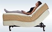 A woman is laying on an adjustable bed with her legs crossed.