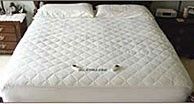 A bed with a white comforter and pillows on it.