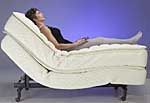 A woman is laying on an adjustable bed.