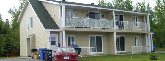 Une maison jaune avec une voiture rouge garée devant