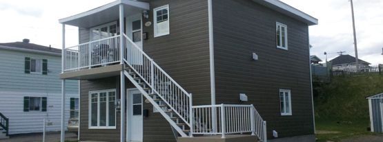Une maison avec des escaliers menant au deuxième étage et un balcon.