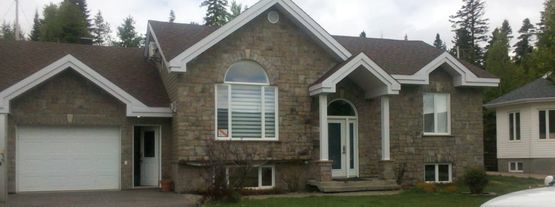 Une grande maison en pierre avec une voiture garée devant.