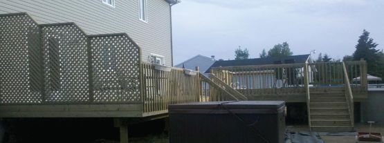 Une maison avec une terrasse en bois et des escaliers devant.