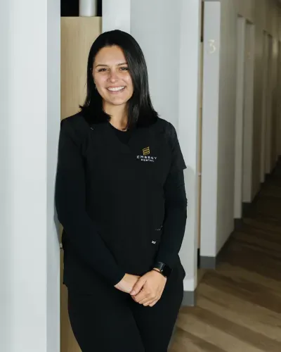 Smiling person in black uniform standing in a hallway beside a doorway