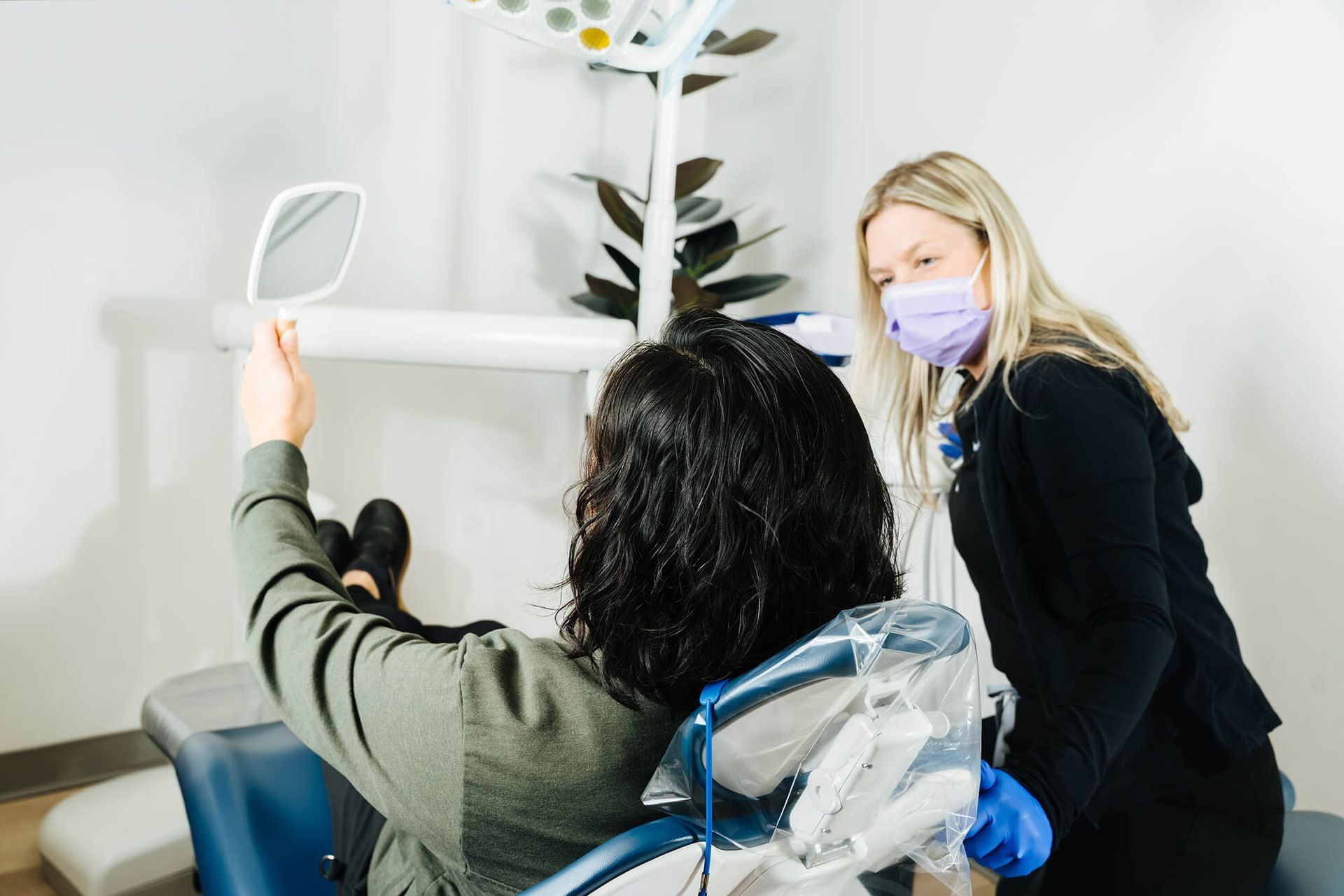 Masked dentist assisting a patient in a bright dental clinic