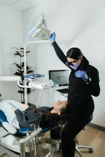Dental assistant adjusting overhead lamp for a reclining patient in a dental exam room