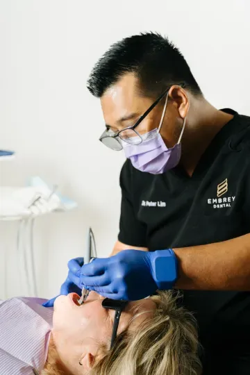 Dentist in mask and blue gloves treating a patient during a dental exam