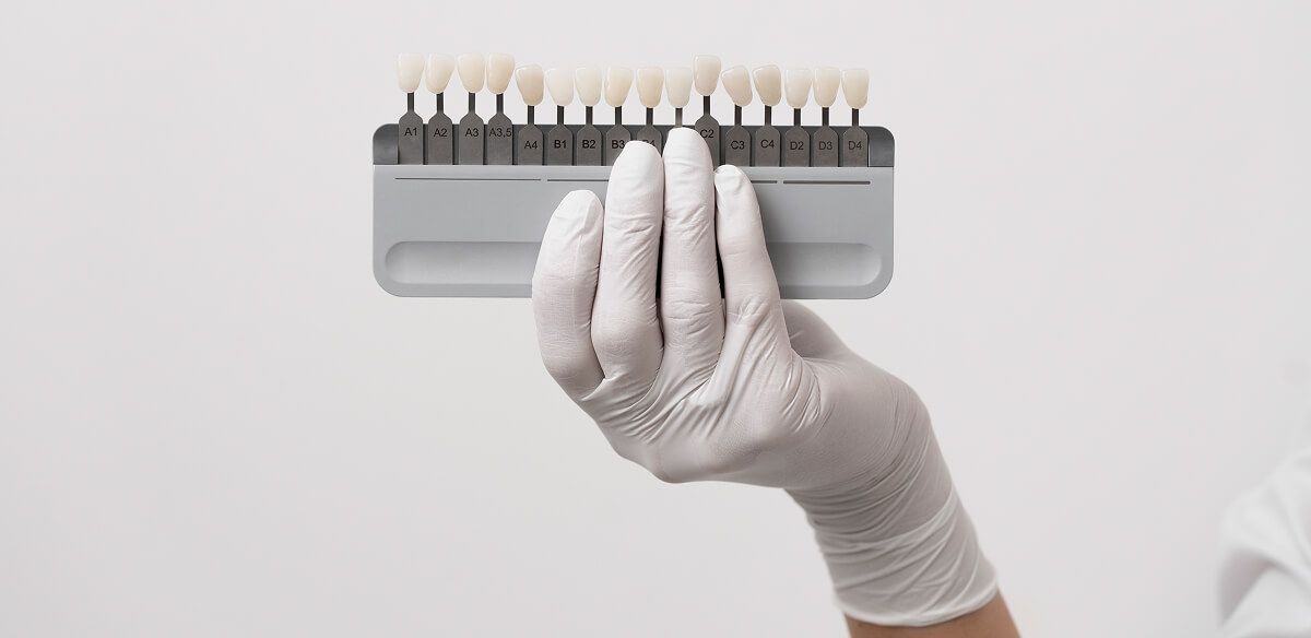 Gloved hand holding a gray toothbrush with white bristles on a light background