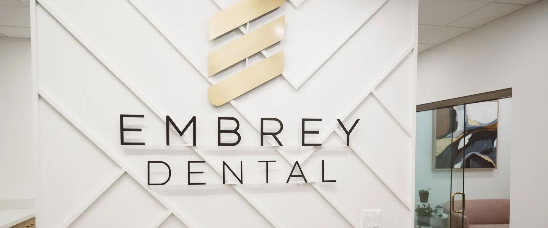 Embrey Dental office sign on a light geometric wall