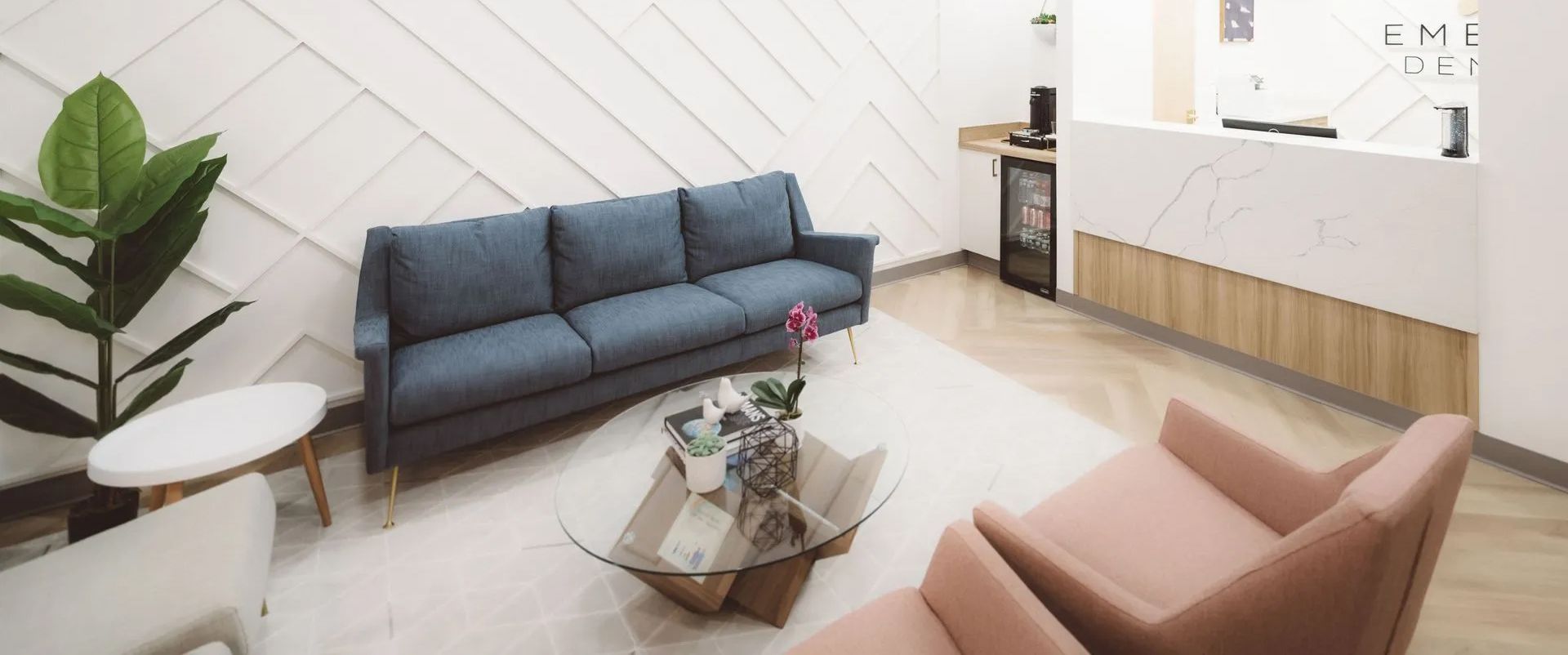 Modern living room with blue sofa, pink chair, coffee table, and wood cabinet