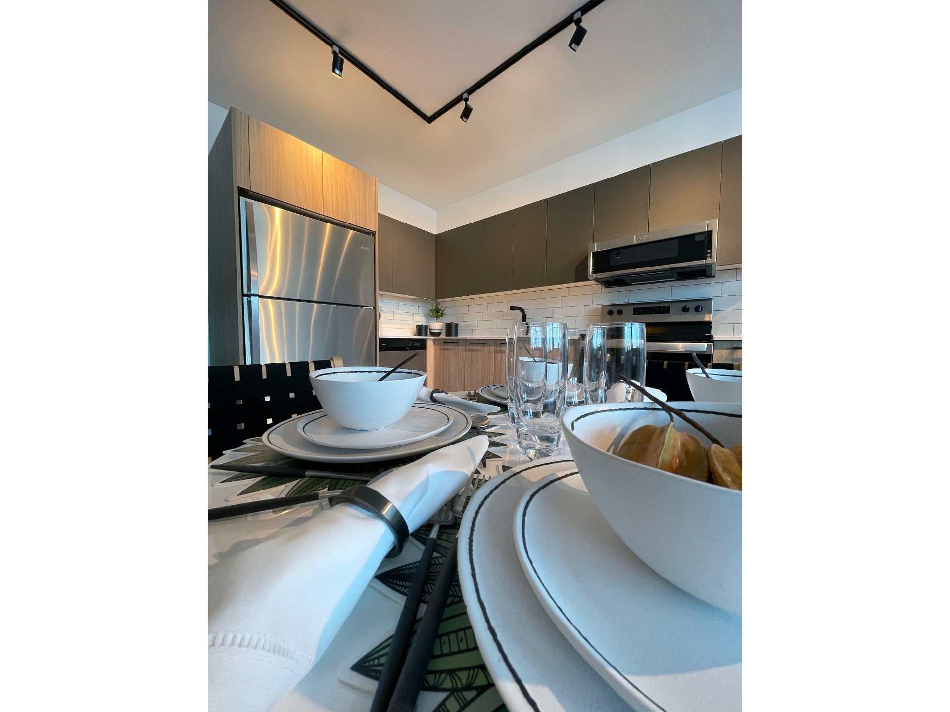 Interior view of a modern apartment kitchen with stainless steel appliances and a dining table.