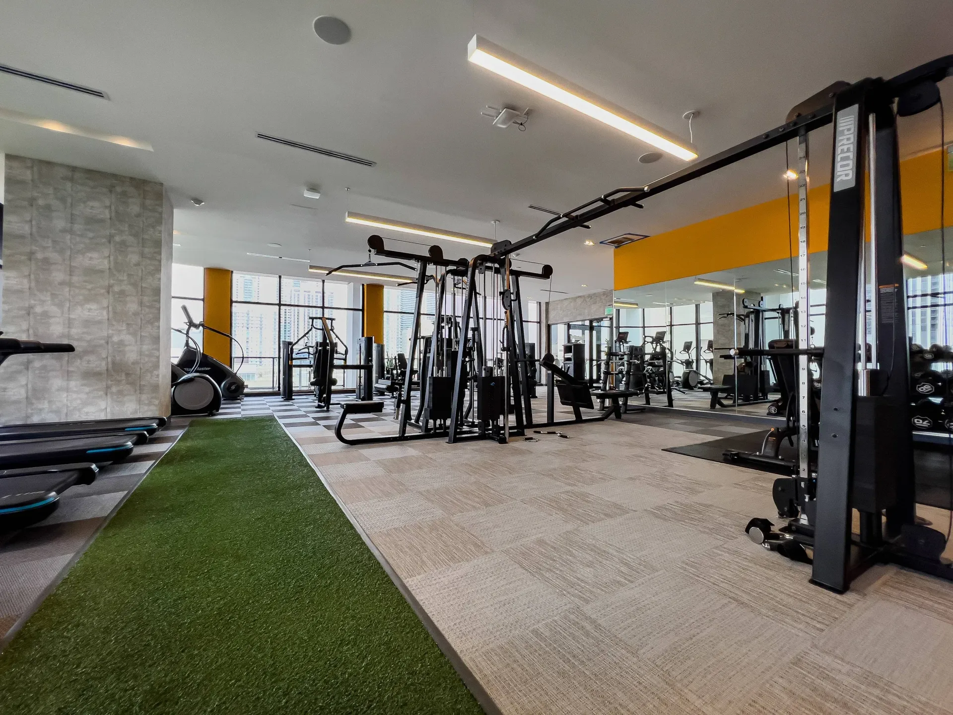 Modern apartment gym with cardio machines, free weights, and turf area.