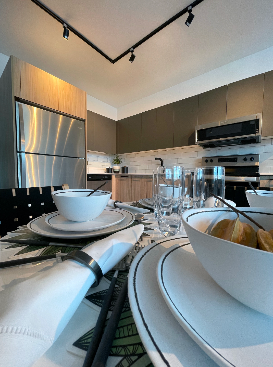 Interior view of a modern apartment kitchen with stainless steel appliances and a dining table.