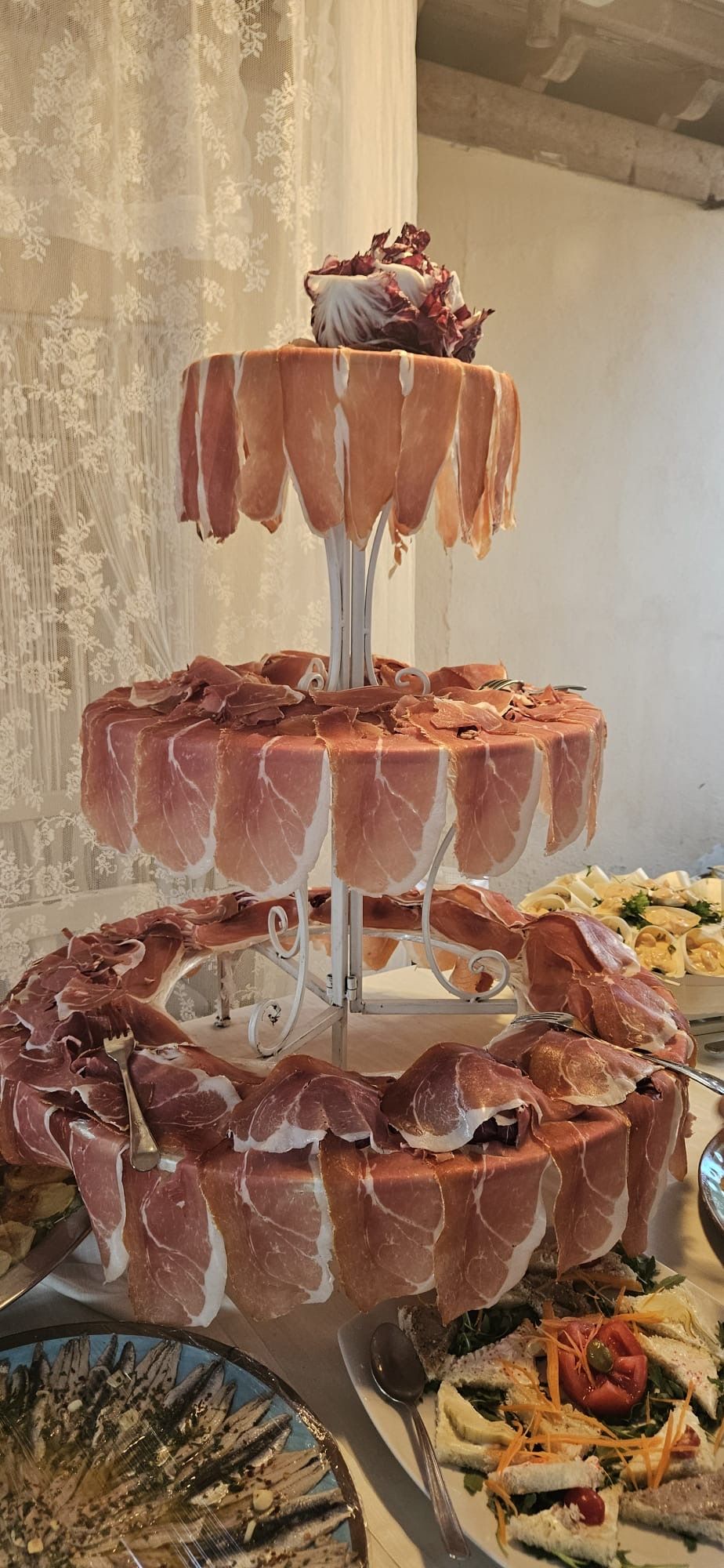 Un piatto di carne a tre livelli, simile a una torta, con prosciutto disposto su ogni strato.