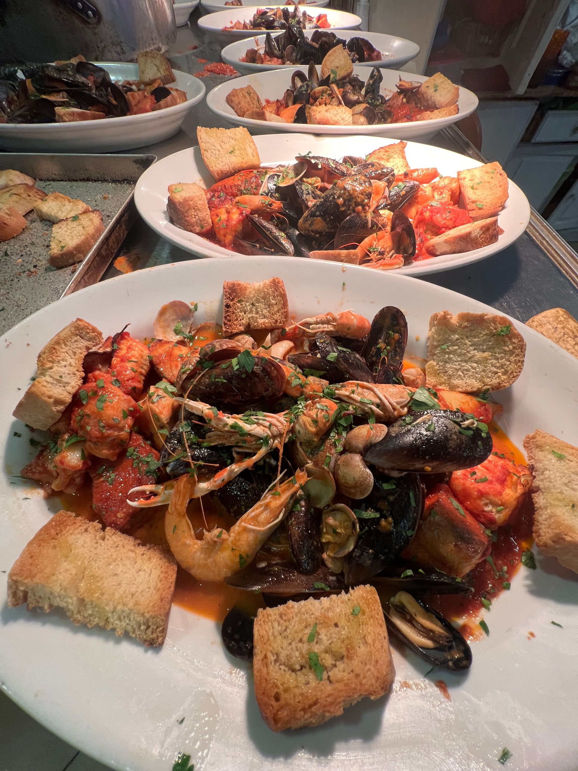 Diversi piatti di stufato di pesce, conditi con crostini.