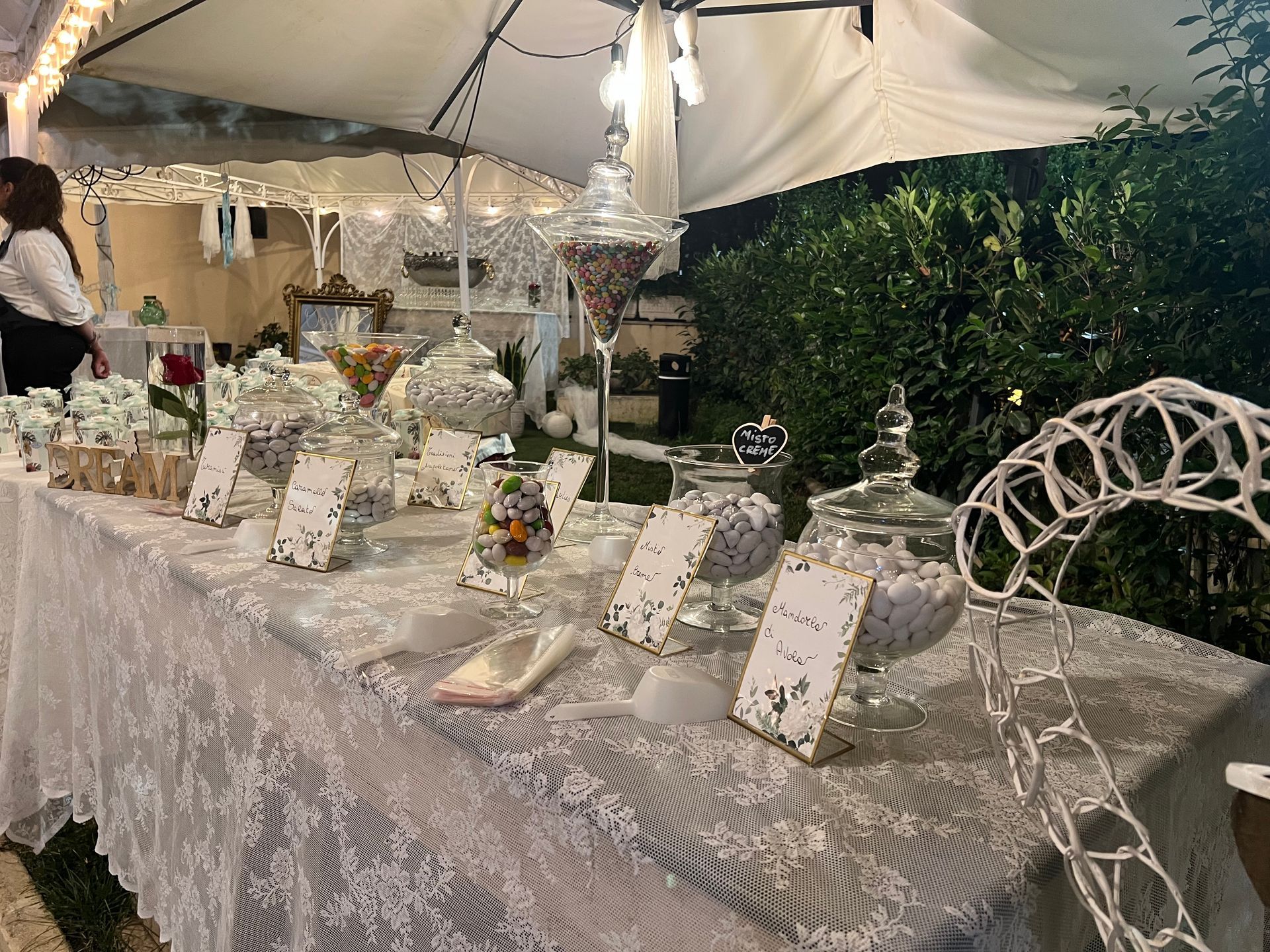 Tavolo da buffet di dolciumi per un evento all'aperto, con vari barattoli di vetro pieni di dolciumi.