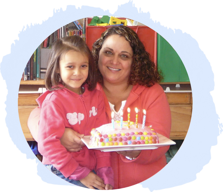 Woman and child holding birthday cake with lit candles.