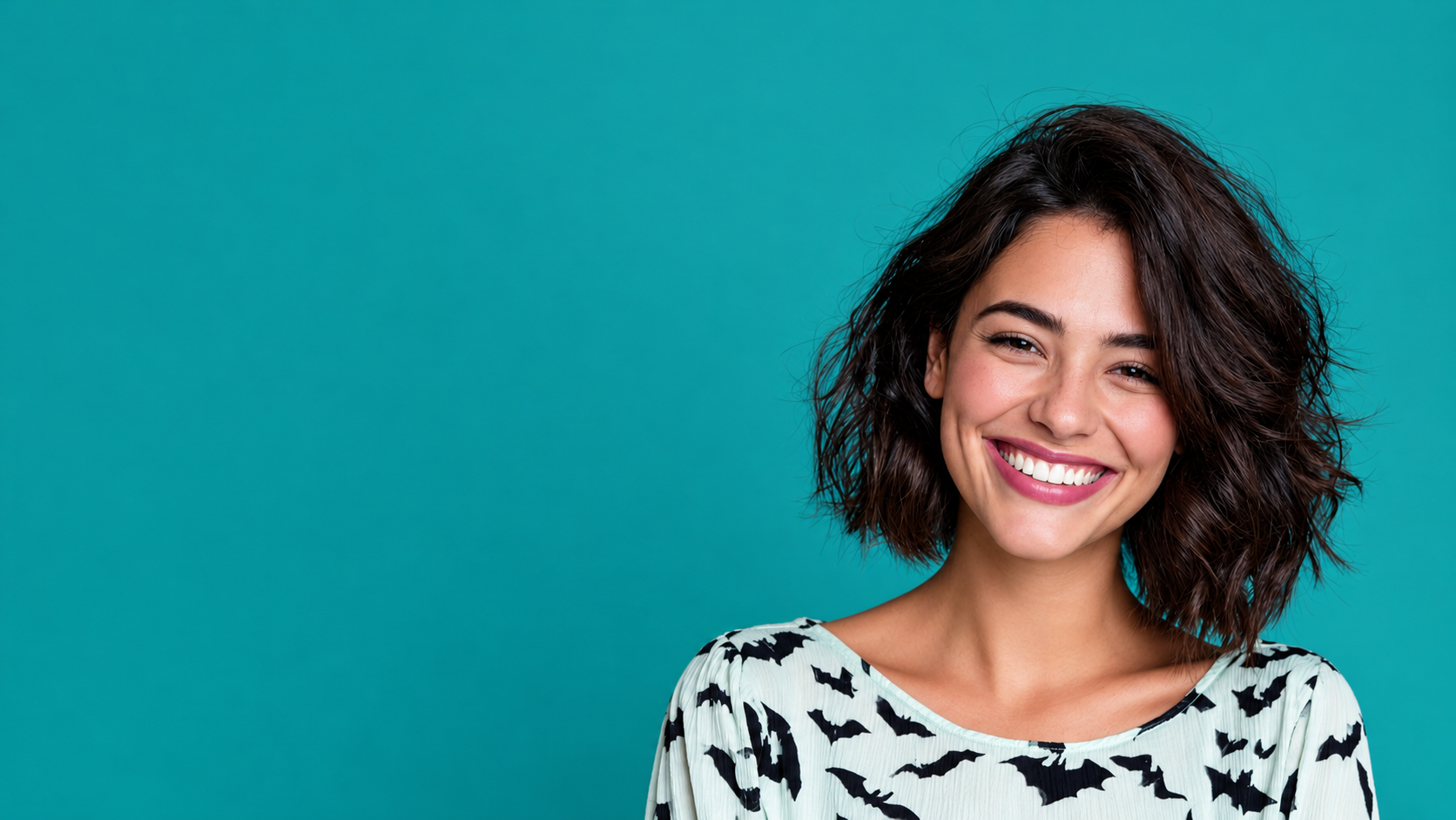 Smiling person in a black-and-white shirt against a teal background