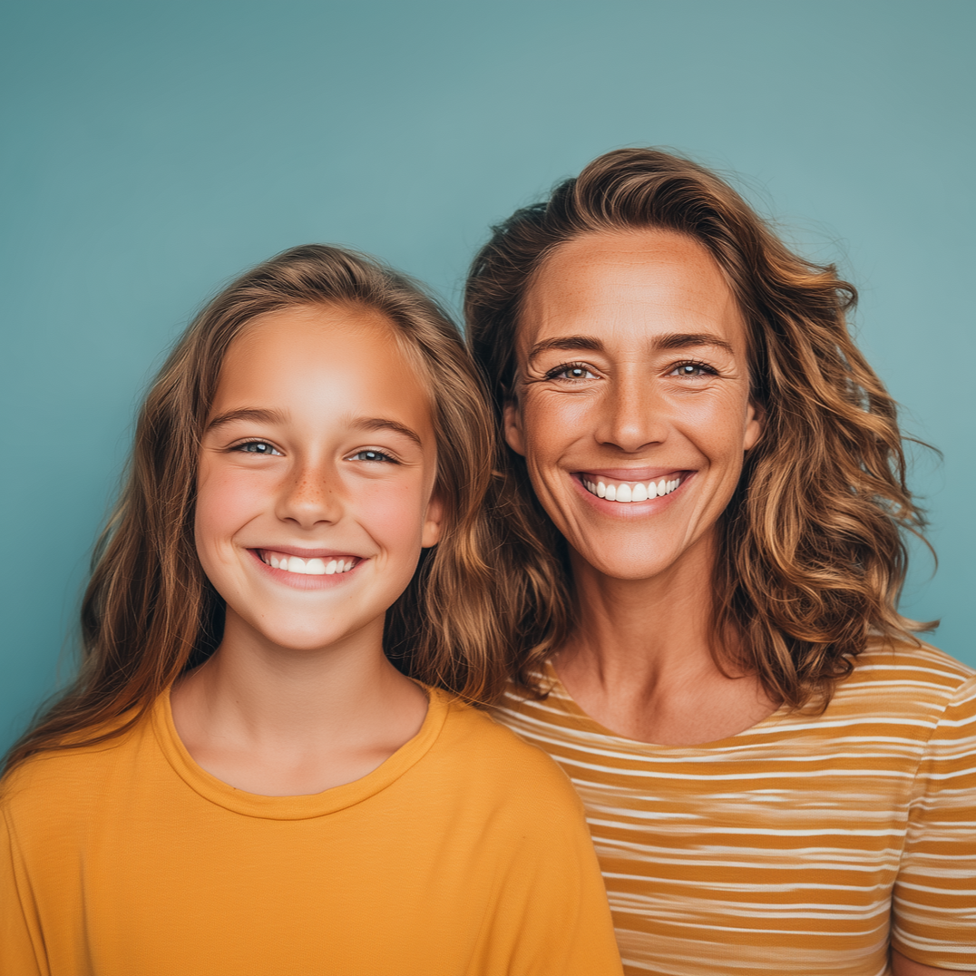 Woman and girl smiling, posing close together in front of a turquoise background.