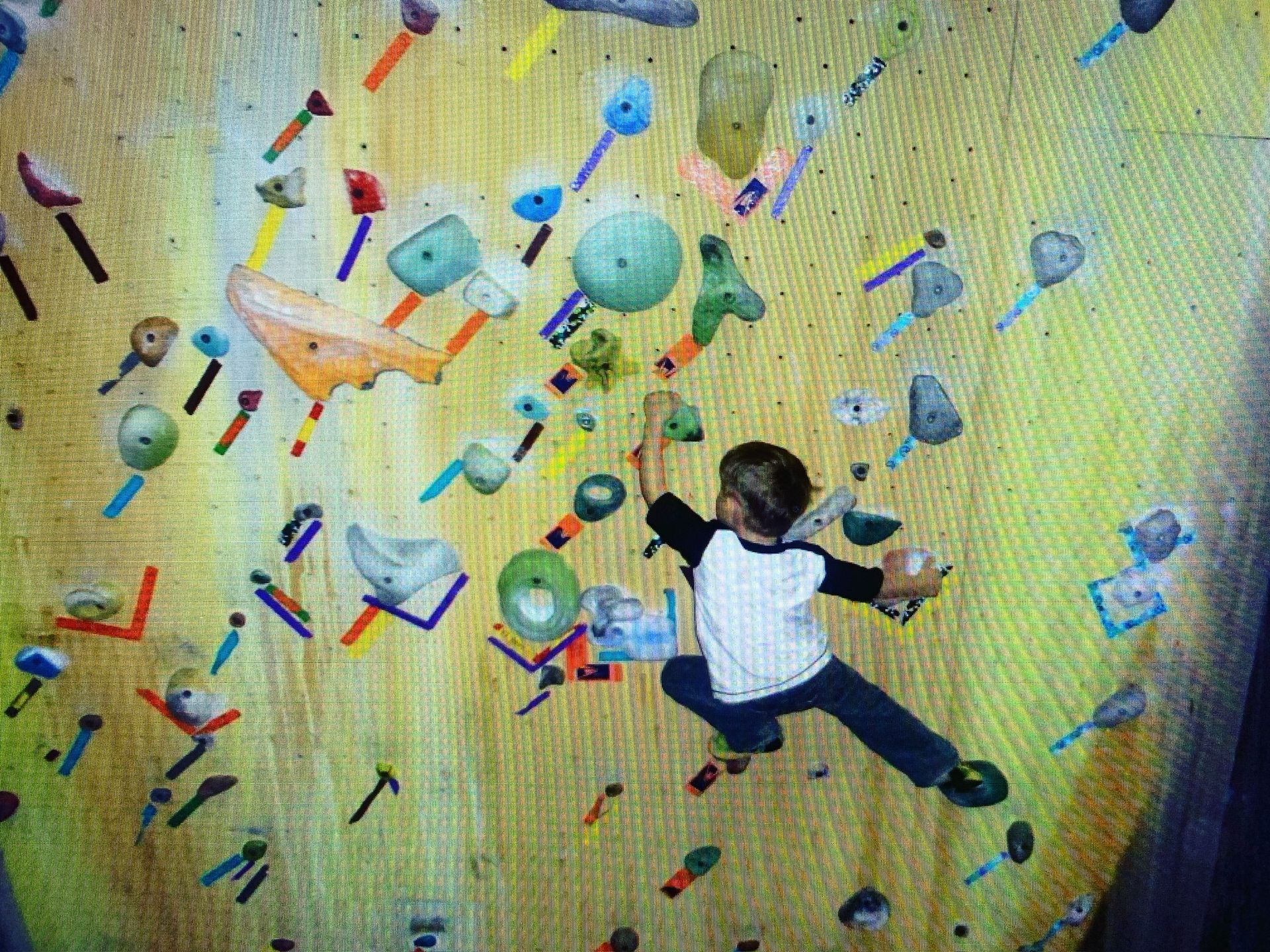 A young boy is climbing a climbing wall.