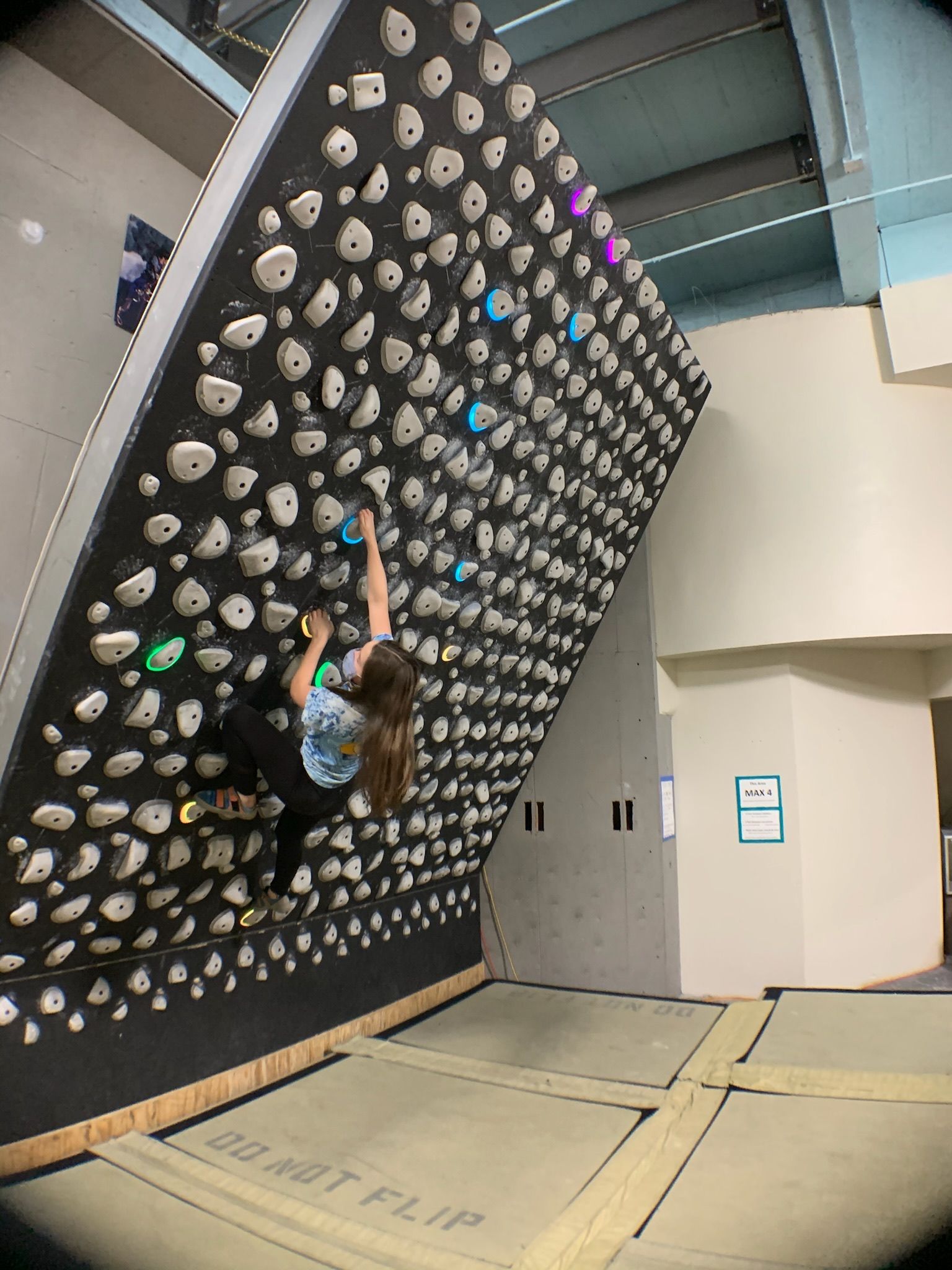 A woman is climbing a climbing wall in a gym.