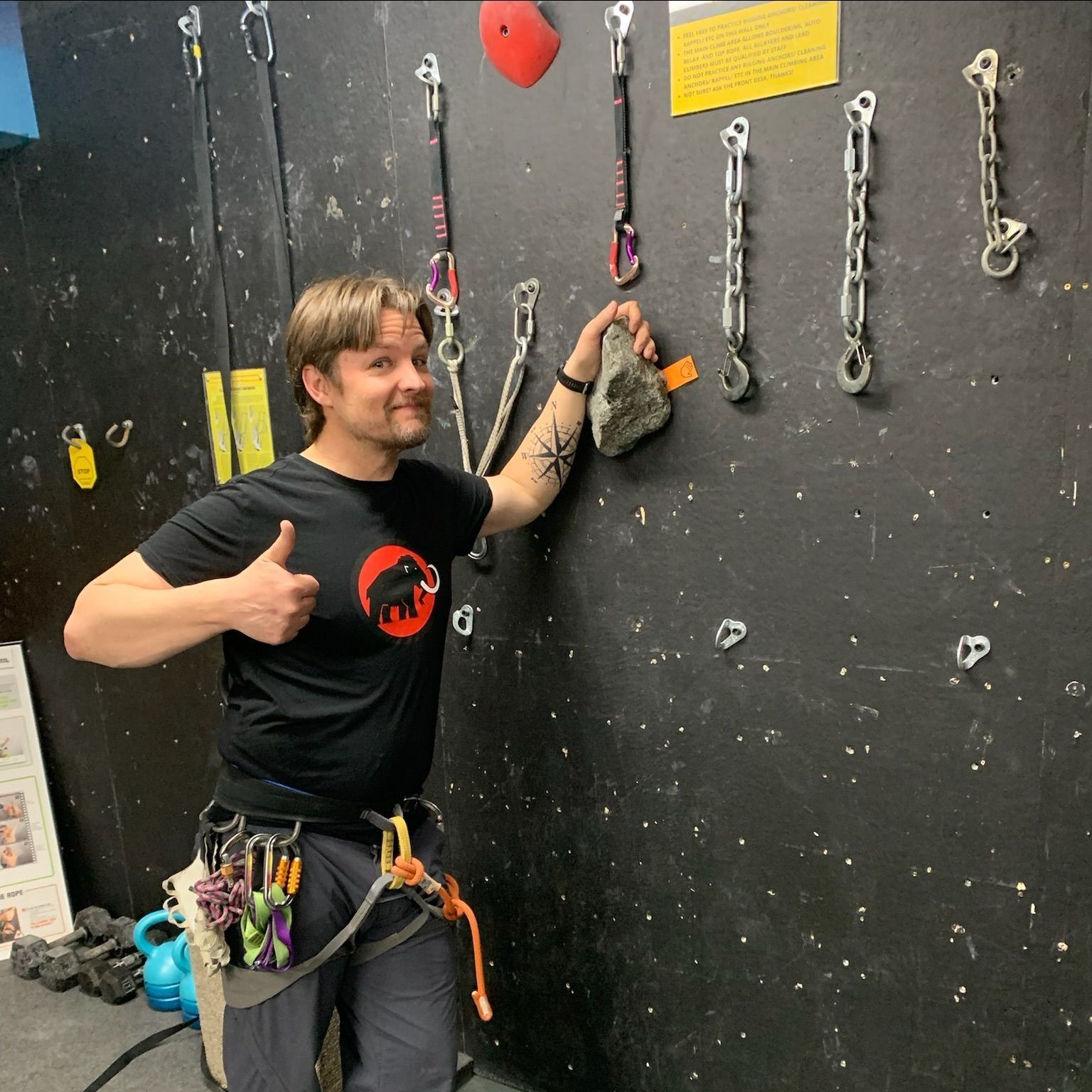 A man giving a thumbs up while standing in front of a black wall