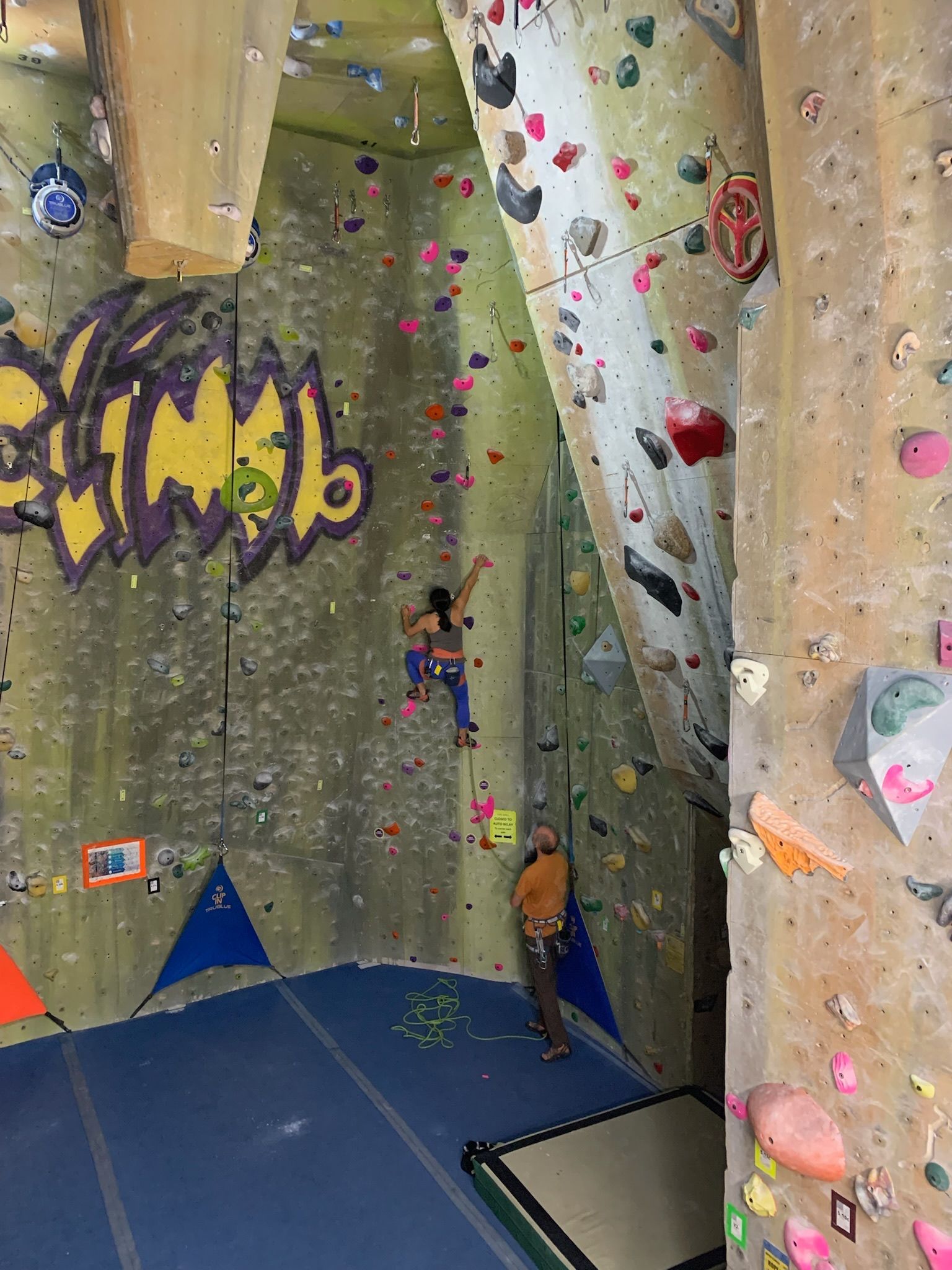 A person is climbing a climbing wall in a gym.