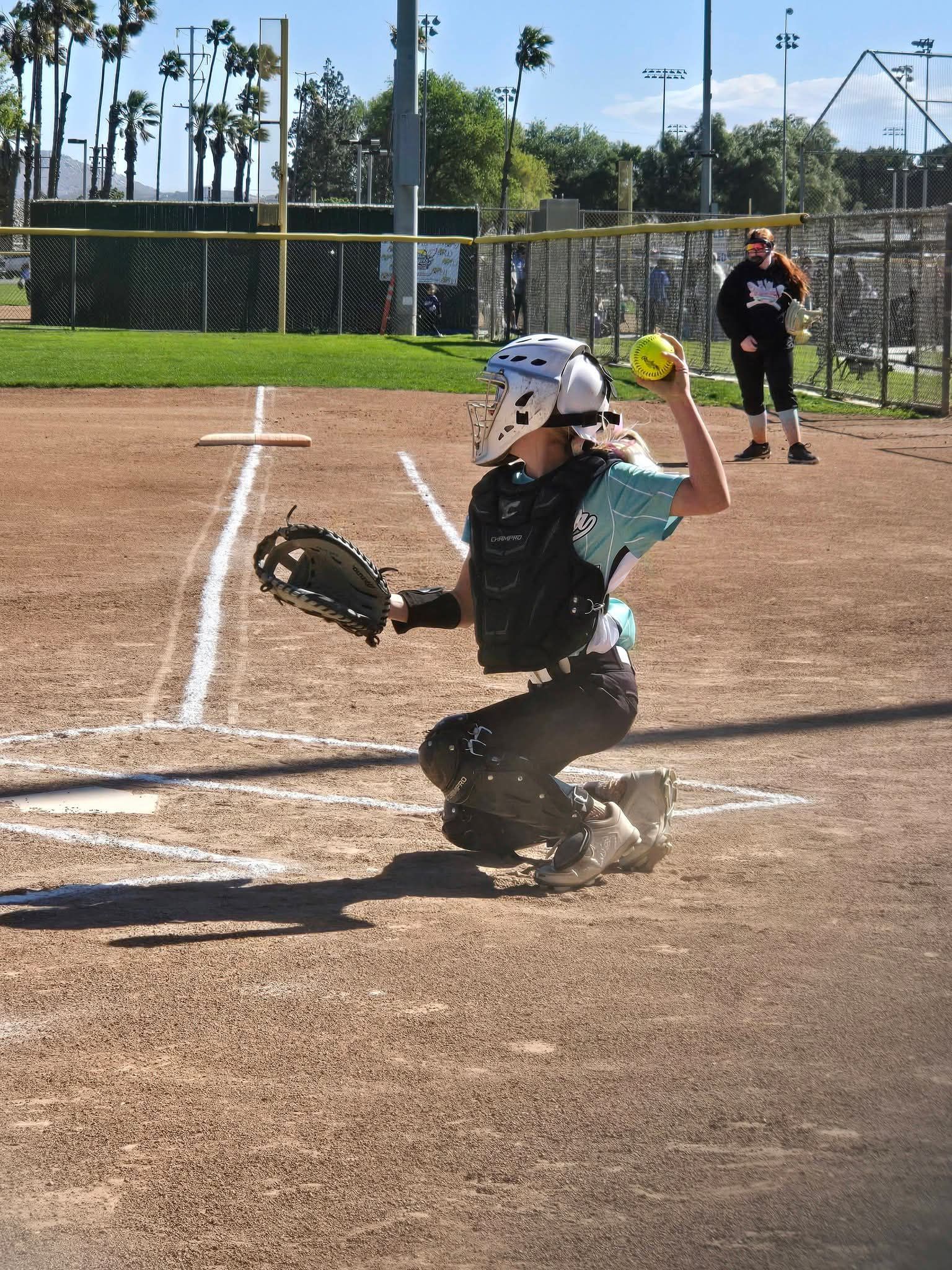 Baseball player sliding into base as another player attempts to catch the ball.