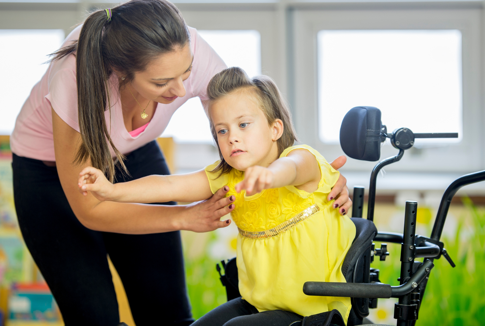 a woman is helping a little girl in a wheelchair .