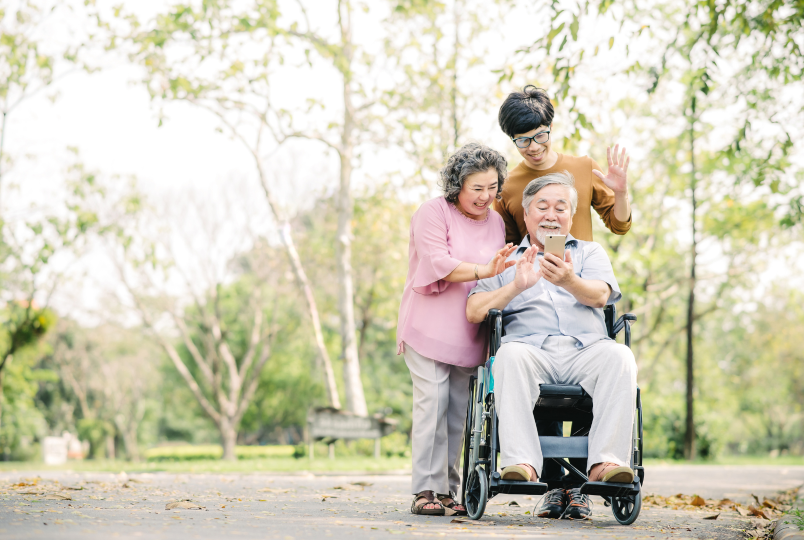 a man in a wheelchair is talking on a cell phone while a woman stands next to him .